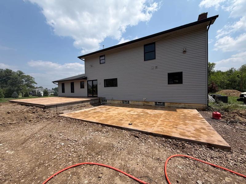 Colored stamped concrete patio poured behind a two-story home