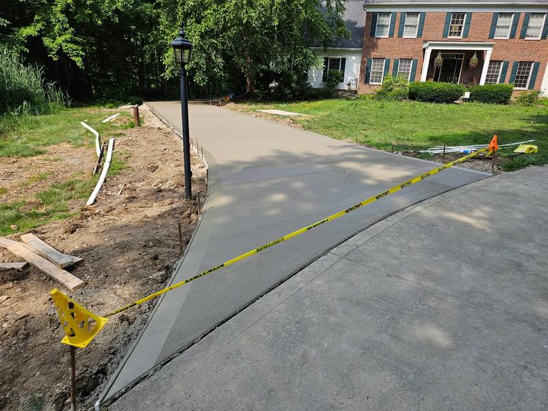 New concrete driveway leading to a brick home