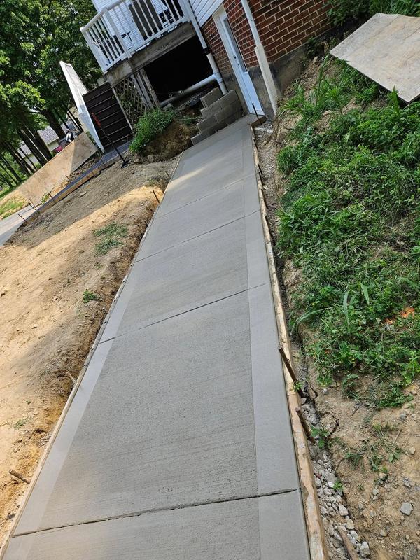 Concrete sidewalk poured along a sloped yard