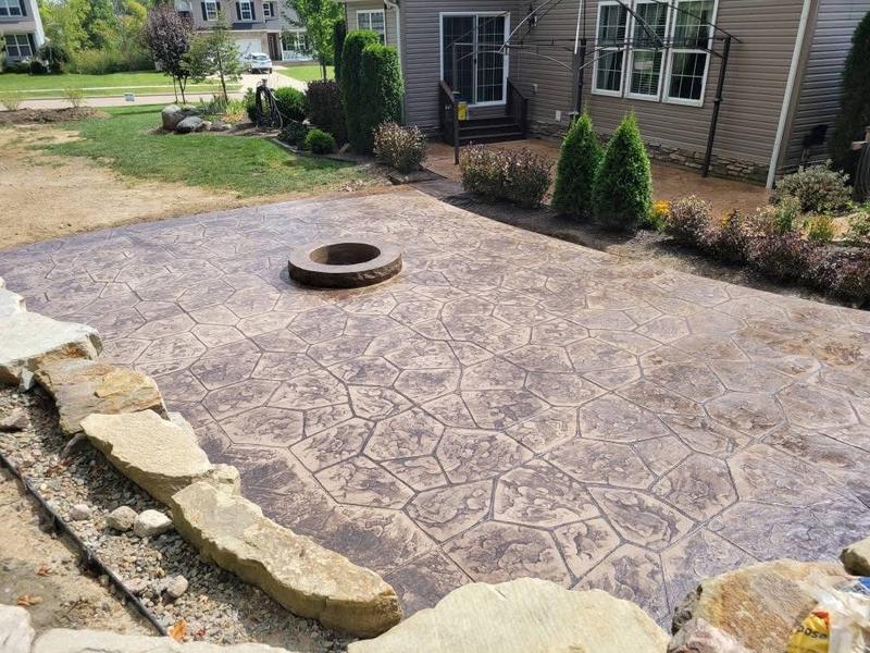 Stamped concrete patio with a built-in fire pit and natural stone border in a Northeast Ohio backyard