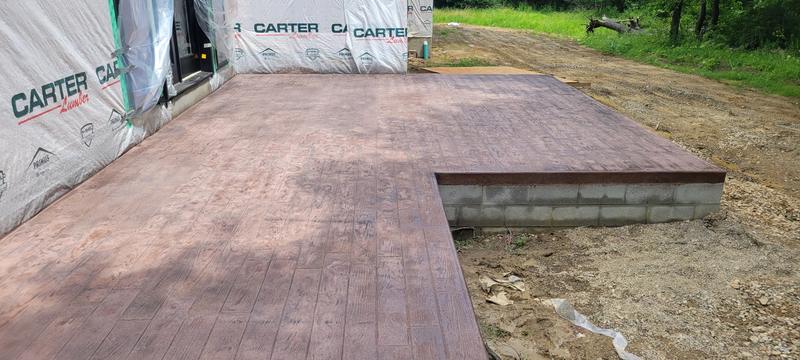 Wood-plank stamped concrete patio with a raised block-wall section at a new home