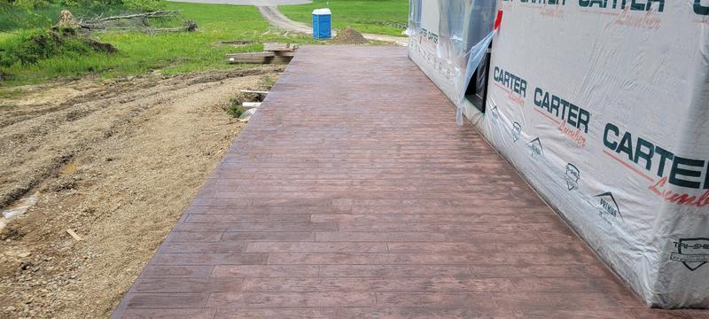 Wood-plank stamped concrete walkway running alongside a new build