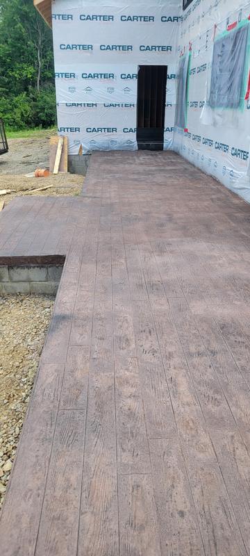 Wood-plank stamped concrete patio and walkway wrapping a new home