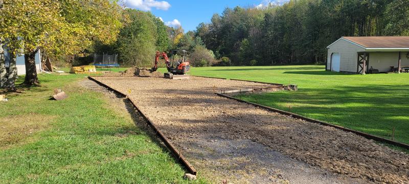 Stone base and forms set for a long concrete pad near a pole barn