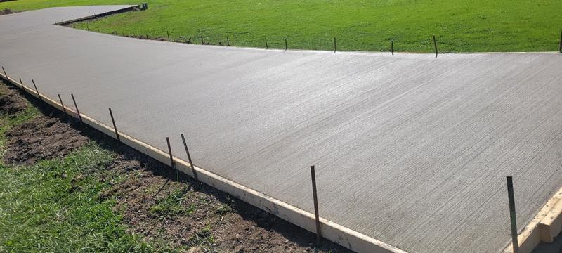 Wide curved concrete driveway finished with a clean broom texture