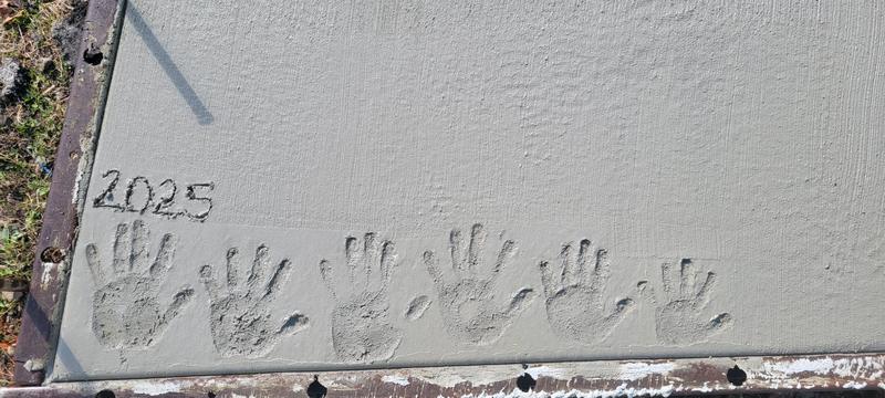 Family handprints and “2025” pressed into a fresh CS & Sons concrete pour